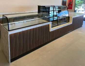 Ceviz ahşap oluklu panelli, gold baza detaylı, beyaz mermer tablalı ve bombeli cam vitrinli lüks cafe teşhir tezgahı