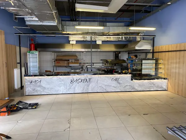 Gri mermer desenli ön panelli, siyah mermer tablalı, LED aydınlatmalı kasa ve cafe bankosu ile entegre pasta teşhir vitrini