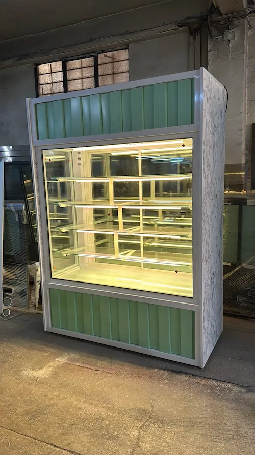 Su yeşili oluklu panelli, beyaz mermer desenli yan kaplamalı, çok raflı ve güçlü led aydınlatmalı dikey pastane teşhir vitrini